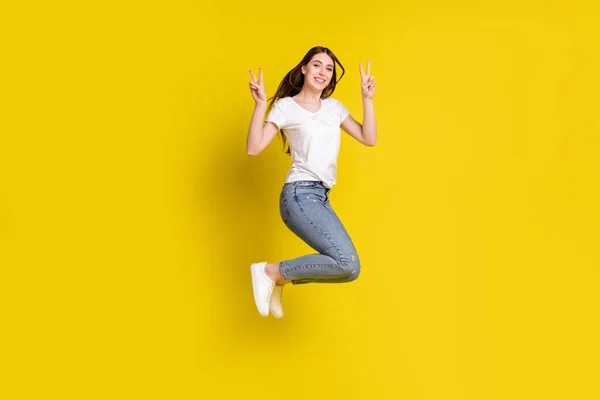 Πλήρες μήκος σώματος μέγεθος φωτογραφία όμορφο κορίτσι χαμογελώντας πηδώντας μέχρι δείχνει v-σημάδι απομονωμένο ζωντανό κίτρινο χρώμα φόντο — Φωτογραφία Αρχείου