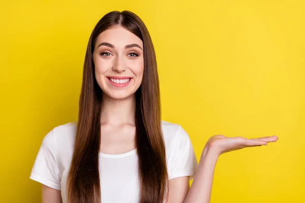 若い陽気な女の子の写真幸せな正の笑顔ショー製品提供広告示唆黄色の色の背景に孤立 — ストック写真