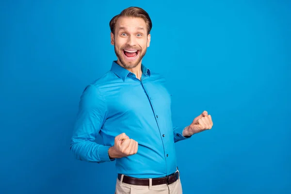 Profil sida foto av ung upphetsad man glad positiv leende fira seger lycklig knytnävar händer isolerade över blå färg bakgrund — Stockfoto