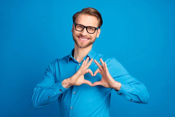 Genç adamın fotoğrafı mutlu mutlu gülümseme parmaklar kalp sembolü aşk mavi arkaplan üzerinde izole aşk — Stok fotoğraf
