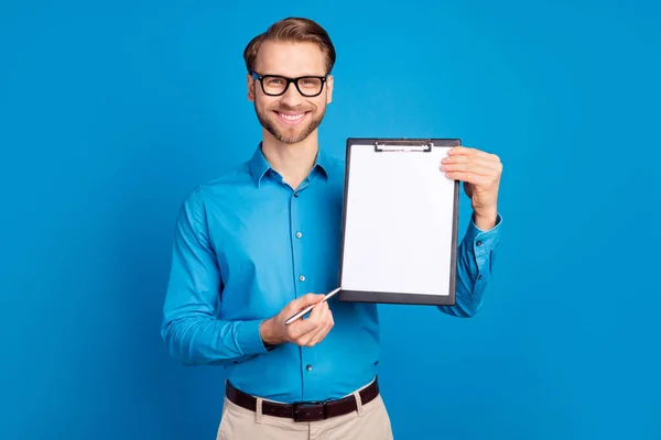 Foto del joven feliz punto de sonrisa positiva lápiz portapapeles documento contrato signo aislado sobre fondo de color azul —  Fotos de Stock