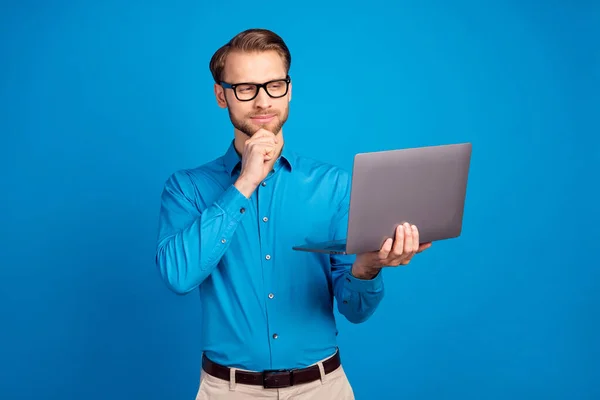 Fénykép a fiatal férfi komoly magabiztos kéz touch áll hiszem, nézd laptop projekt jelentés elszigetelt felett kék színű háttér — Stock Fotó
