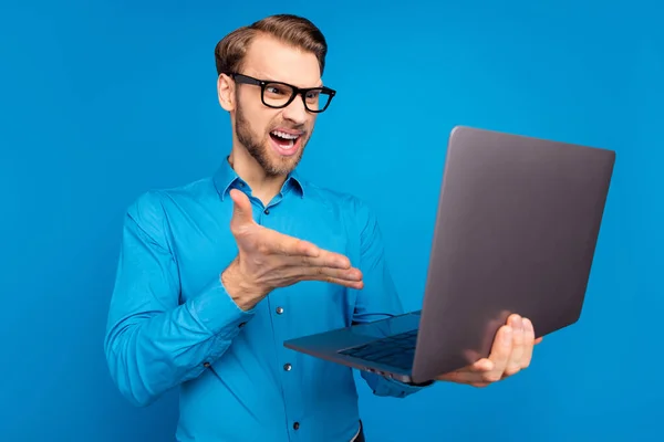 Profil boční fotografie mladého muže nešťastný naštvaný šílený křičet problém mluvit videokall notebook izolované přes modré barvy pozadí — Stock fotografie