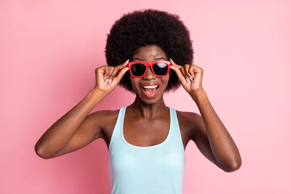 Retrato de optimista morena agradable rizado dama tacto gafas llevar top azul aislado sobre fondo de color rosa — Foto de Stock