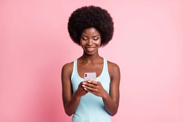 Foto de otimista bonito morena encaracolado senhora segurar telefone desgaste azul top isolado no fundo cor-de-rosa pastel — Fotografia de Stock