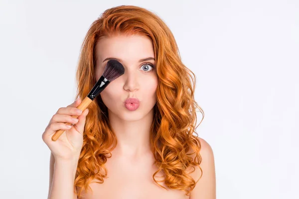 Foto retrato de modelo joven con el pelo rojo rizado puché labios mantener maquillaje cepillo ocultando ojo aislado sobre fondo de color blanco — Foto de Stock