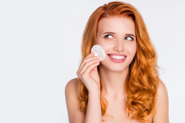 Foto retrato chica pelirroja sonriendo quitando maquillaje con disco de algodón aislado sobre fondo de color blanco — Foto de Stock