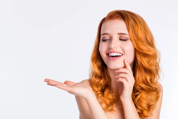 Foto retrato de menina bonita com cabelo encaracolado vermelho sorrindo olhando espaço em branco mantendo na mão isolado no fundo de cor branca — Fotografia de Stock