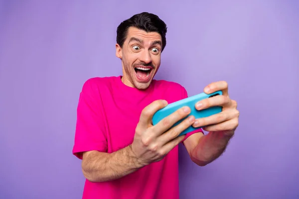 Foto van jonge vrolijke vrolijke opgewonden gekke man gamer spelen video game op smartphone geïsoleerd op paarse kleur achtergrond — Stockfoto