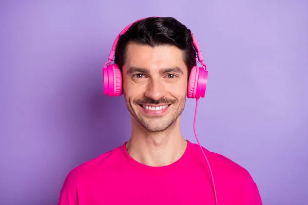 Foto de joven feliz alegre buen humor sonriente hombre escuchando música en auriculares aislados sobre fondo de color púrpura — Foto de Stock