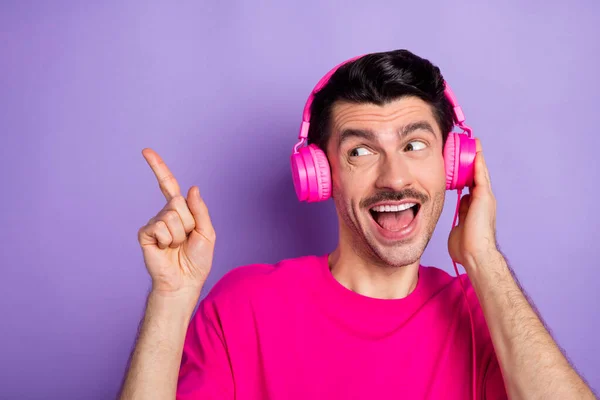 Foto van jonge vrolijke vrolijke opgewonden man in koptelefoon wijzen vinger copyspace adverteren geïsoleerd op violette kleur achtergrond — Stockfoto