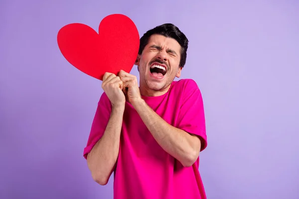 Retrato de una persona joven ojos cerrados boca abierta gritar manos fuertes sostener tarjeta de corazón de papel aislado sobre fondo de color púrpura —  Fotos de Stock