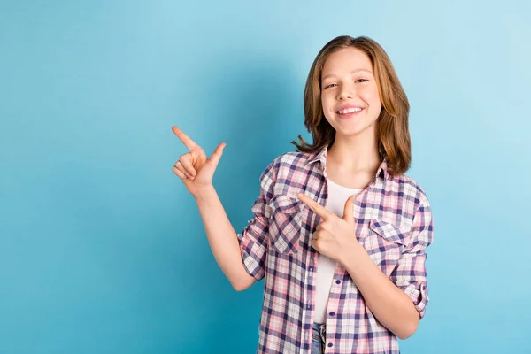 Foto de engraçado encantador menina pequena desgaste xadrez camisa apontando dedos vazio espaço isolado azul cor fundo — Fotografia de Stock