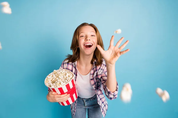 Portrait of positive excited school girl hand throwing popcorn toothy smile look camera isolated on blue color background — Stock Photo, Image