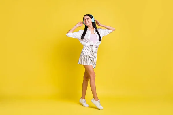 Full size foto van vrolijke mooie vrouw dragen headset lopen kijken lege ruimte geïsoleerd op gele kleur achtergrond — Stockfoto