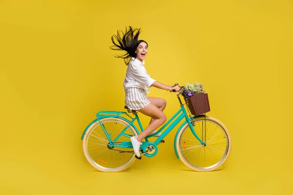 천연색 배경에 고립된 야생 화를 싣고 자전거를 타고 있는 행복하게 웃는 젊은 소녀의 사진 — 스톡 사진