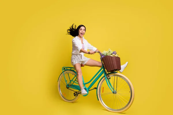 유쾌하고 명랑 한 젊은 소녀가 노란색 배경에 극도로 자전거를 타고 있는 전체 크기 사진 — 스톡 사진