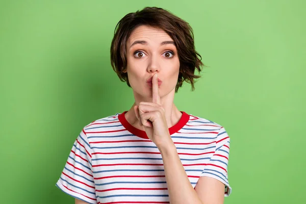 Retrato de desconcertado joven dama dedo cubriendo labios boca mirada cámara no dicen aislado sobre fondo de color verde — Foto de Stock