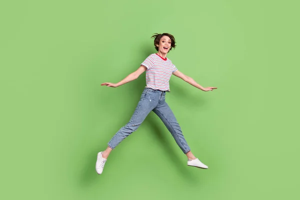 Volledige lichaamslengte uitzicht van vrij vrolijke grappige meisje springen wandelen plezier geïsoleerd over groene pastel kleur achtergrond — Stockfoto
