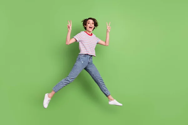 全长体形全景相当快乐而惊奇的女孩跳跃显示出V字形孤立的绿色彩色背景 — 图库照片
