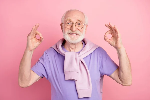 Фотопортрет пожилого человека счастливый позитивный мужчина показывает нормальный жест с пальцами, изолированными на пастельно-розовом фоне — стоковое фото