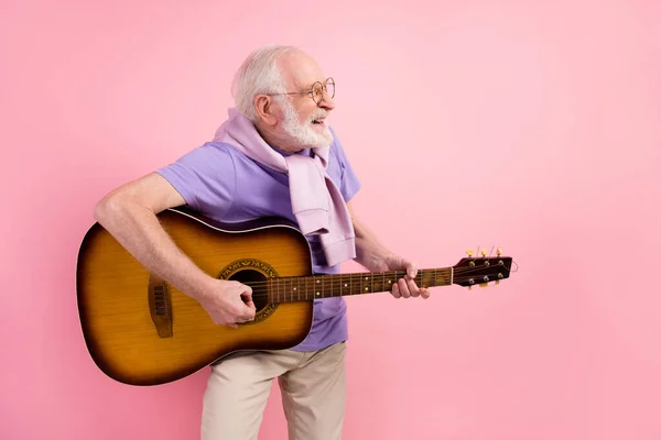 Emeklinin resim portresi gitar çalarken gülümsüyor pastel pembe arka planda izole edilmiş boş bir alana bakıyor. — Stok fotoğraf