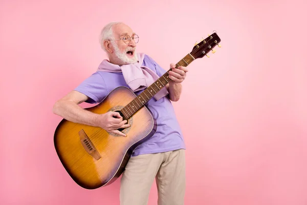 Pembe arka planda izole edilmiş rock yıldızı gibi gitar çalan komik mutlu büyükbabanın fotoğrafı. — Stok fotoğraf