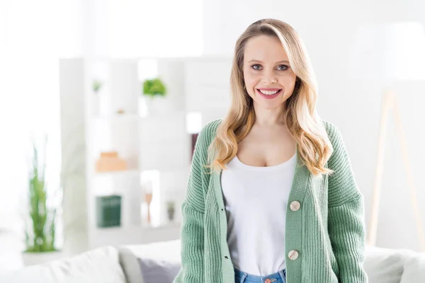 Portret van een aantrekkelijk vrolijk golvend meisje met knusse kleding die thuis verblijft licht witte huiskamer binnen — Stockfoto