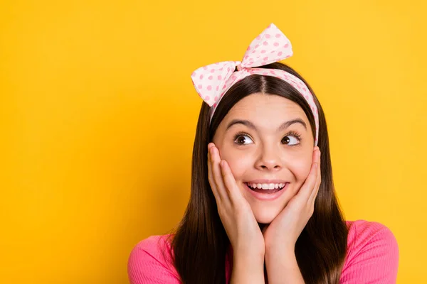 Foto av glada söt liten skolflicka klädd rosa t-shirt armar kindben ser tomt utrymme isolerad gul färg bakgrund — Stockfoto