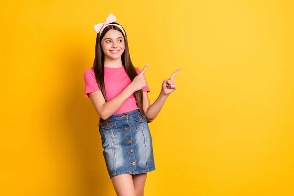 Foto de animado bonito pequena estudante vestida camiseta rosa olhando apontando dois dedos espaço vazio sorrindo isolado cor amarela fundo — Fotografia de Stock