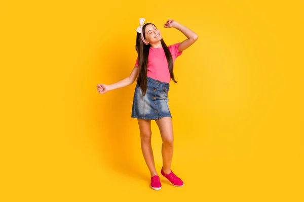 自信を持って面白い学校の女の子の写真はピンクのTシャツを着て笑顔ダンス孤立した黄色の背景 — ストック写真