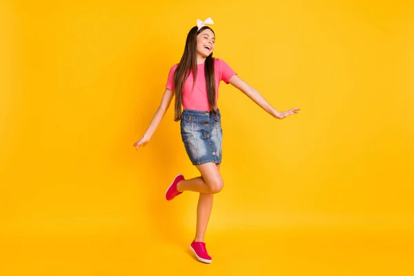 Foto von entzückenden glänzenden kleinen Schulmädchen gekleidet rosa T-Shirt tanzen lächelnd isoliert gelbe Farbe Hintergrund — Stockfoto