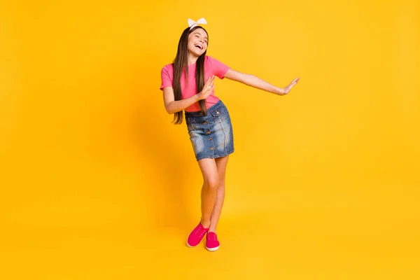 Photo of funny charming school girl wear pink t-shirt smiling dancing isolated yellow color background — Stock Photo, Image