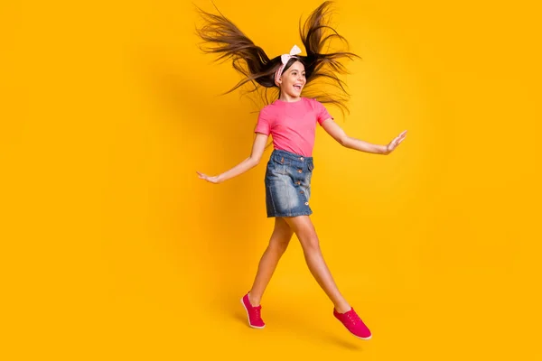 Photo of charming sweet school girl wear pink t-shirt smiling jumping high looking empty space isolated yellow color background — Stock Photo, Image