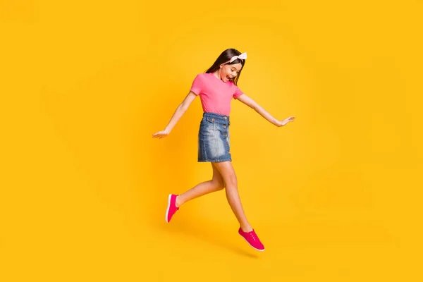 Foto de doce impressionado menina da escola usar rosa t-shirt sorrindo salto de alta aparência calçado isolado cor amarela fundo — Fotografia de Stock