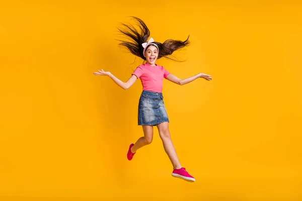 Foto de adorável engraçado escola menina desgaste rosa t-shirt sorrindo saltando alto isolado cor amarela fundo — Fotografia de Stock