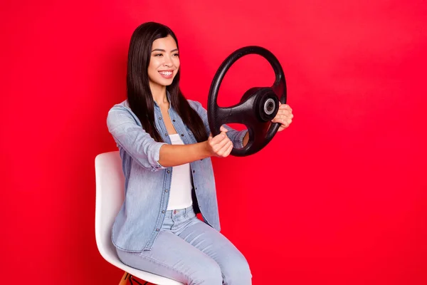 Retrato de conteúdo atraente menina alegre qualificado sentado no volante cadeira equitação isolado sobre fundo de cor vermelha brilhante — Fotografia de Stock