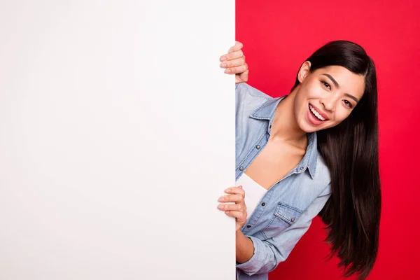 Портрет привабливої веселої дівчини, що тримає великий порожній плакат оголошення ізольовано на яскраво-червоному тлі — стокове фото