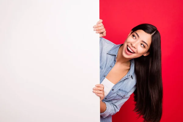 Портрет привлекательной веселой любопытной девушки с большим пустым плакатом рекламу промо изолированы на ярко-красном фоне — стоковое фото