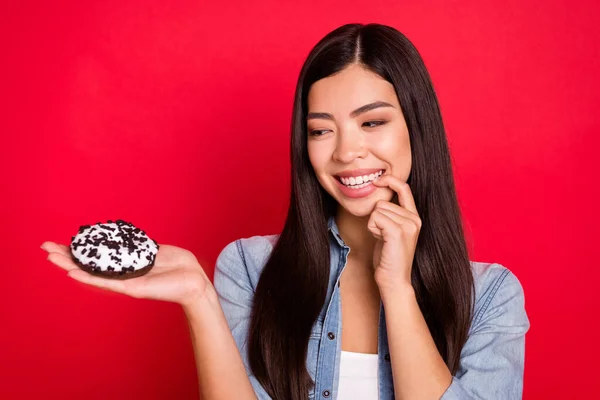 Portrait d'attrayant mode faim fille gaie tenant donut souhait veulent ongle mordant isolé sur fond de couleur rouge vif — Photo