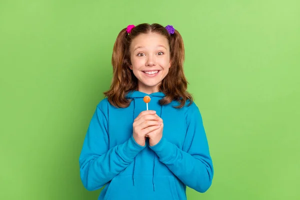 Foto de alegre feliz bonito positivo menina segurar as mãos doce pirulito sorriso isolado no fundo de cor verde — Fotografia de Stock