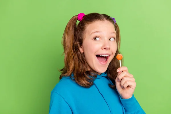 Foto de alegre feliz positivo adolescente olhar vazio espaço segurar doces isolado no fundo de cor verde — Fotografia de Stock