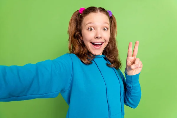 Photo of cheerful positive little girl make fingers v-sign make selfie isolated on green color background — Stock Photo, Image