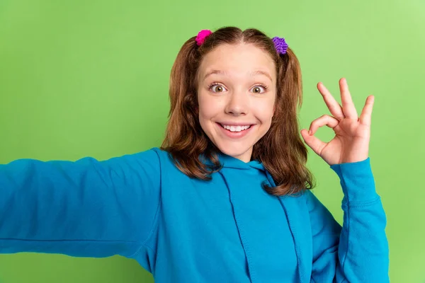 Photo of happy brunette tail haired excited little girl make selfie show okay sign isolated on green color background — Stock Photo, Image