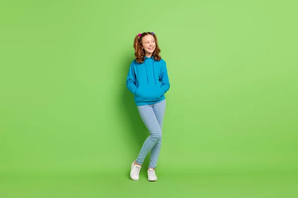 Foto de longitud completa de aspecto positivo adolescente feliz pequeño espacio vacío sostener manos bolsillos aislados en el fondo de color verde — Foto de Stock