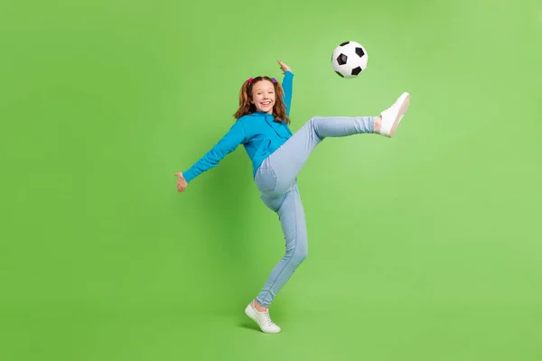 Foto de comprimento total de feliz agradável menina jogar futebol bom humor chute isolado no fundo de cor verde — Fotografia de Stock