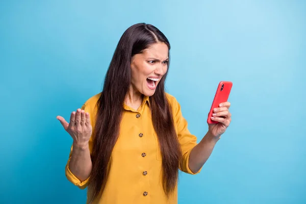 Portret van ontevreden dame staren telefoon open mond schreeuwen luid slecht nep nieuws geïsoleerd op blauwe kleur achtergrond — Stockfoto