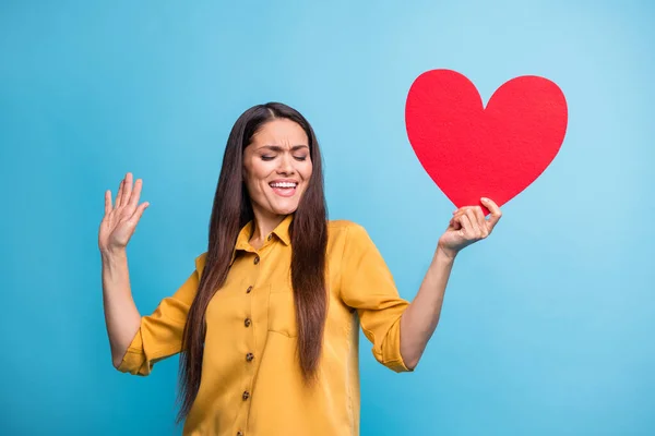 Retrato de brazo de dama agradable positivo sostiene la postal de corazón de papel disfruta bailando aislado sobre fondo de color azul —  Fotos de Stock