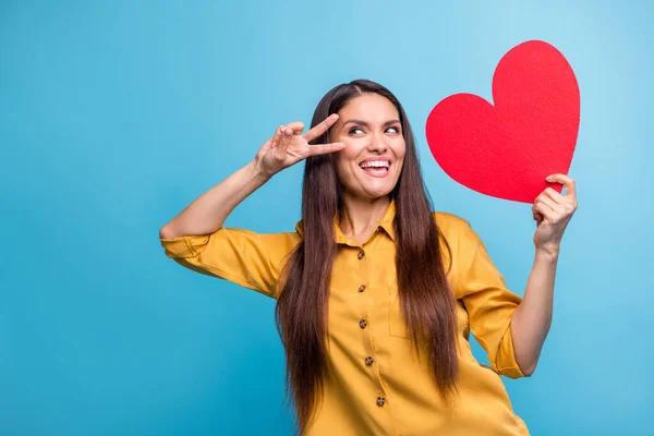 Foto retrato de modelo curioso olhando espaço vazio mostrando cartão de coração v-sinal rindo isolado em fundo de cor azul vívido — Fotografia de Stock