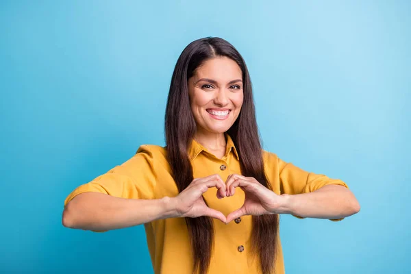 Φωτογραφία πορτρέτο του χαρούμενου μοντέλου που δείχνει το σχήμα της καρδιάς με τα δάχτυλα χαμογελώντας απομονώνονται σε ζωντανό φόντο μπλε χρώμα — Φωτογραφία Αρχείου